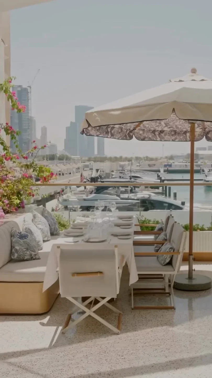 Elegant outdoor dining setup at Morgana Taormina, Sicily, with a view of yachts in the marina.