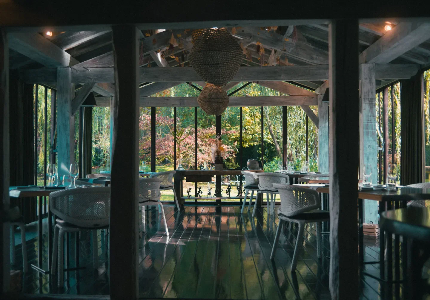 Interior dining at Moulin d'Alotz restaurant in Biarritz, with wooden beams and garden views.