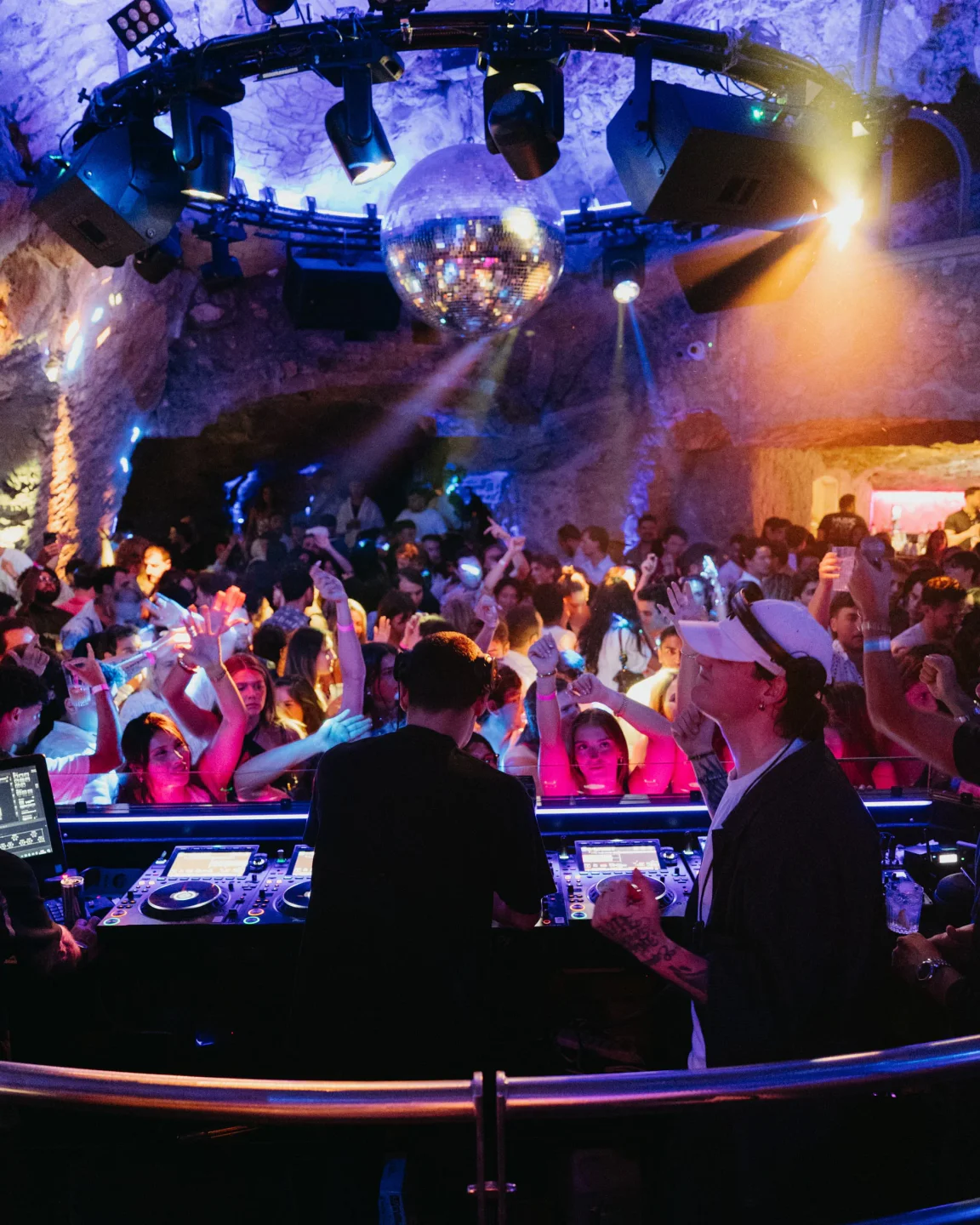 DJs performing for a lively crowd at Music on the Rocks nightclub in Amalfi Coast with disco ball.