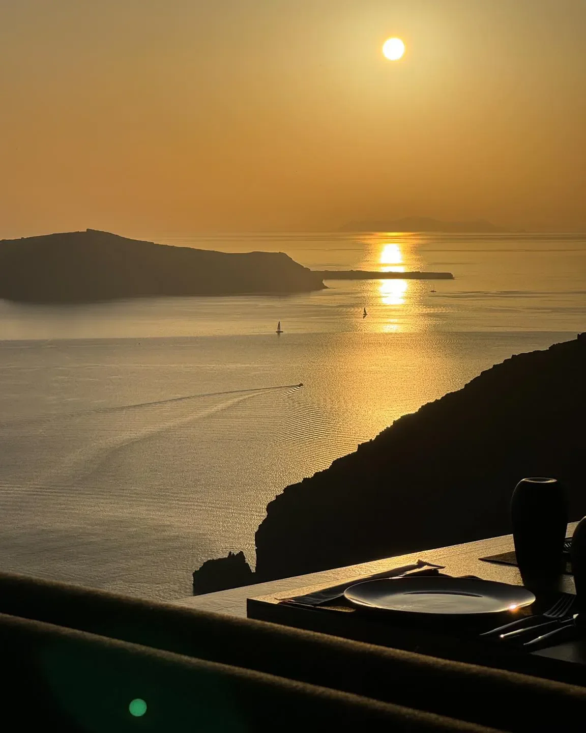 Sunset view from Mylos Champagne restaurant in Santorini, with table setting and sea