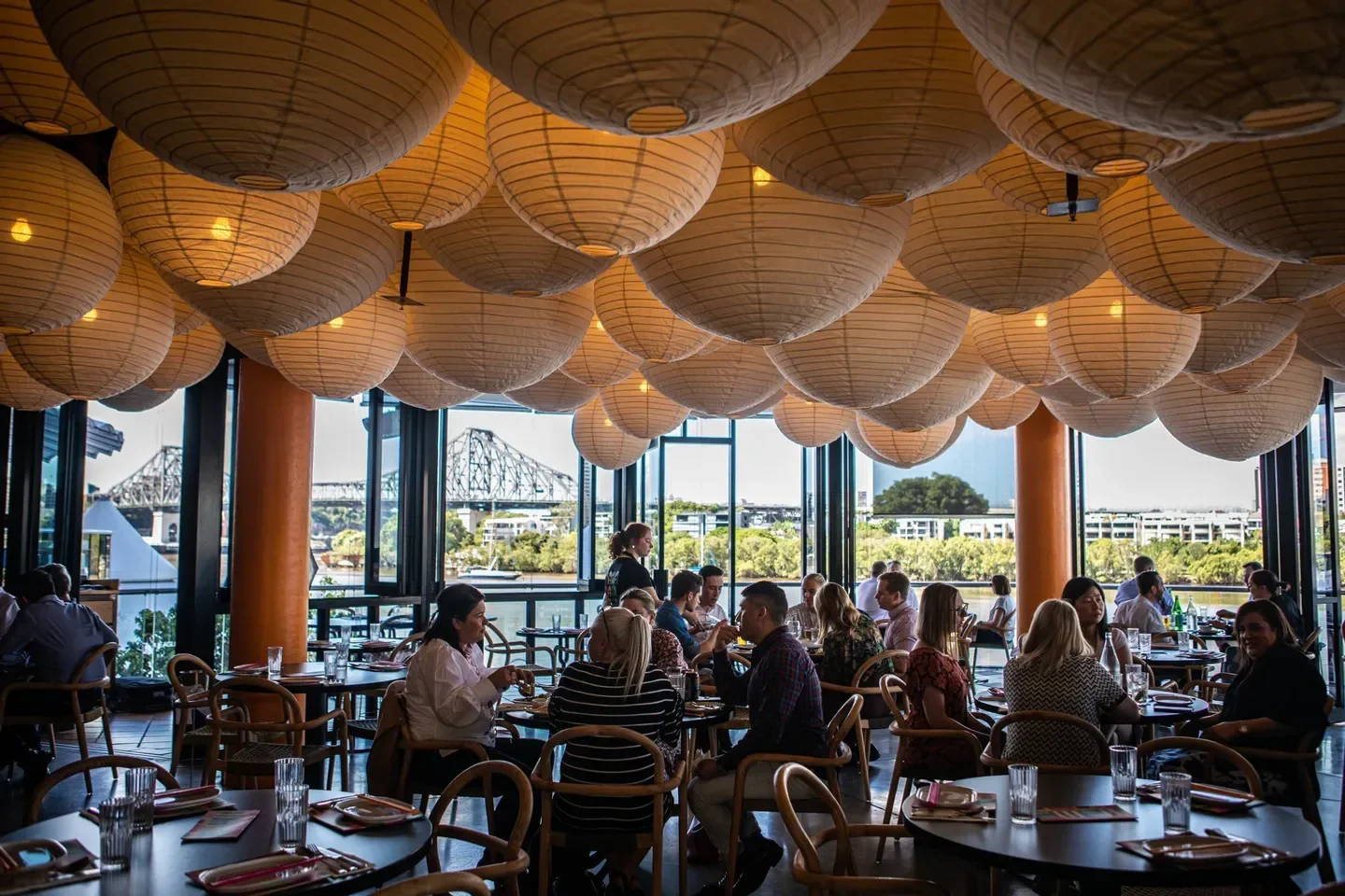 Interior of Naga Thai restaurant in Brisbane with paper lanterns and city views.