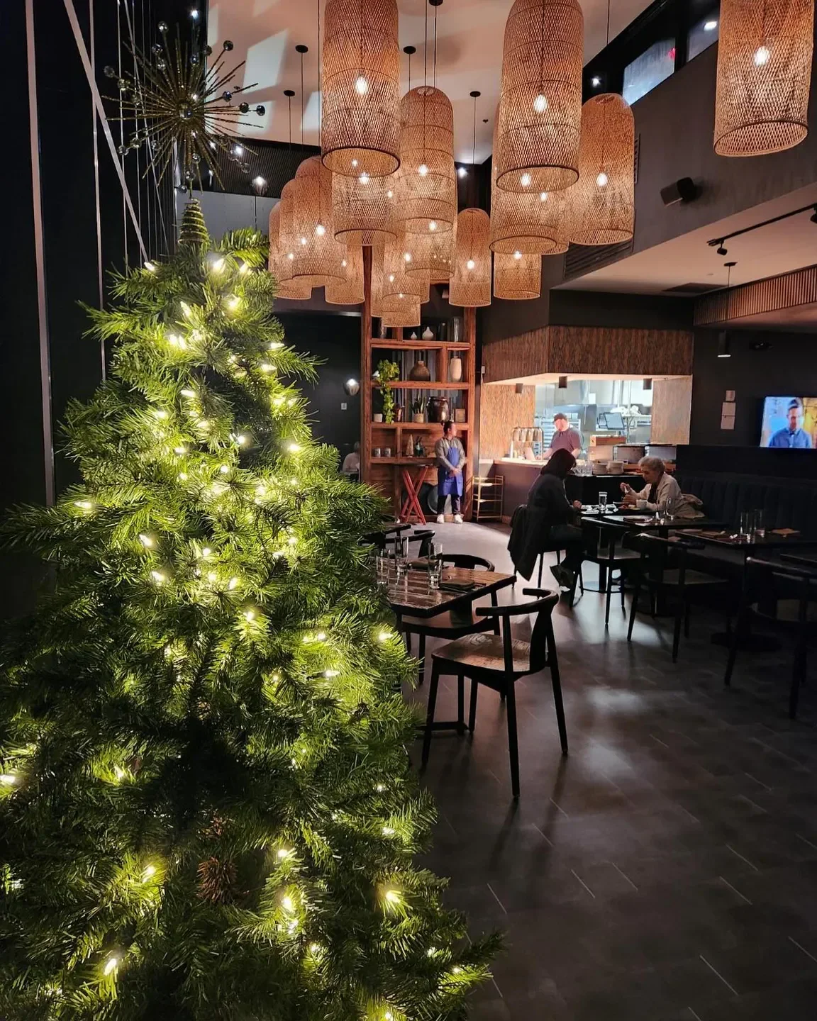 Cozy interior of NAMI restaurant in Louisville with Christmas tree and hanging lights.