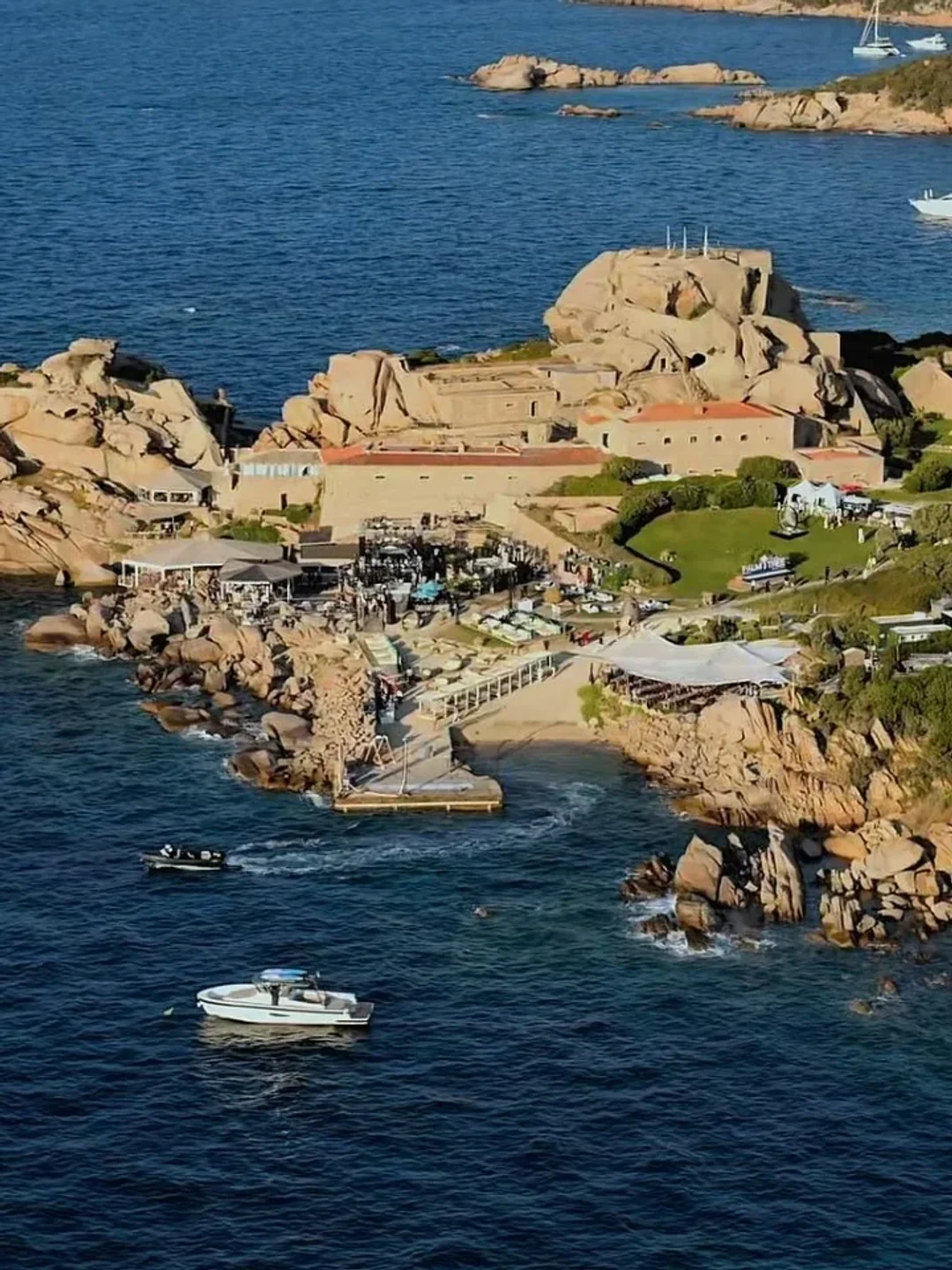 Nammos Beach club in Porto Cervo with vibrant beach scene and boats in the blue sea.