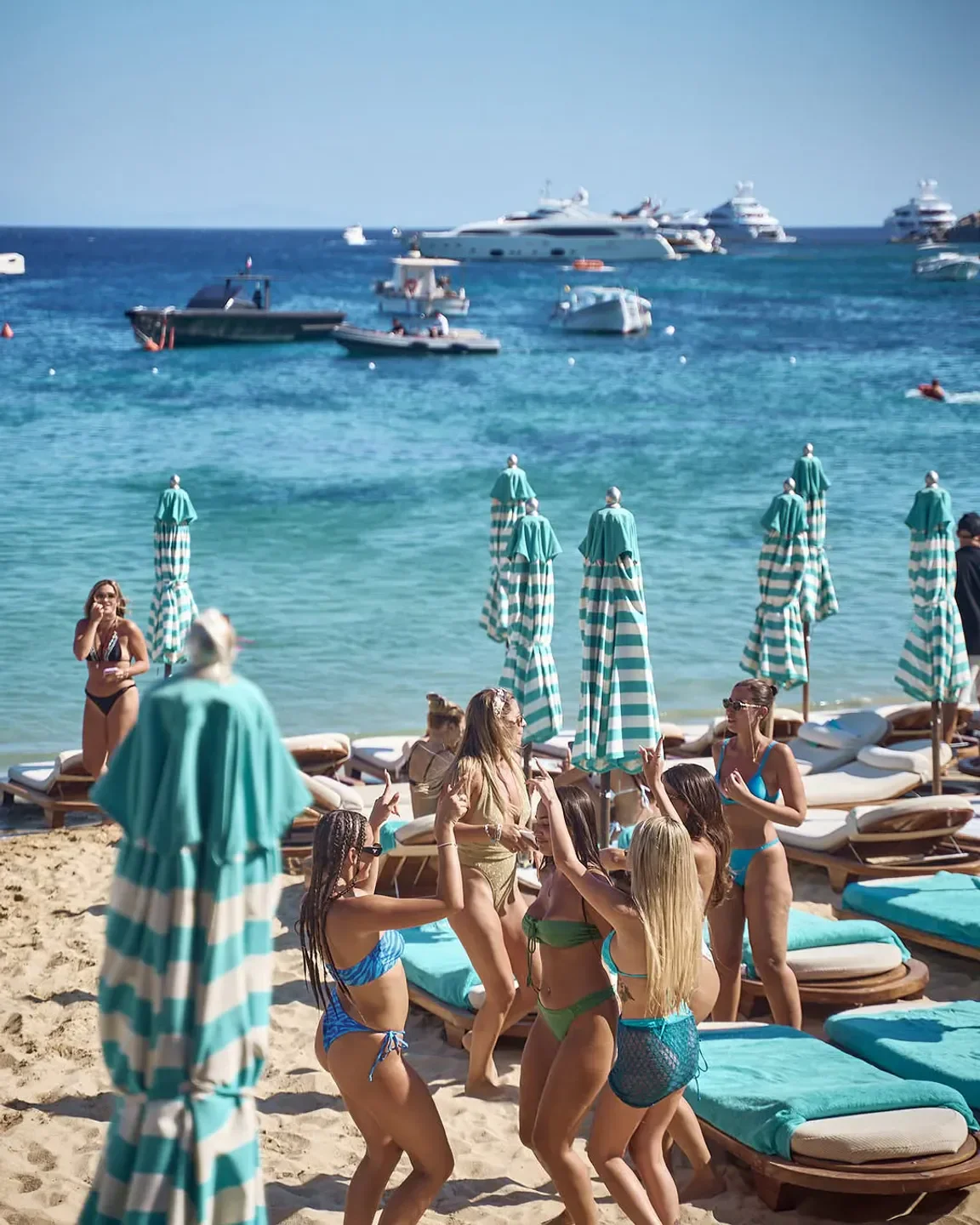 Beach party at Nammos Mykonos with turquoise umbrellas and ocean views