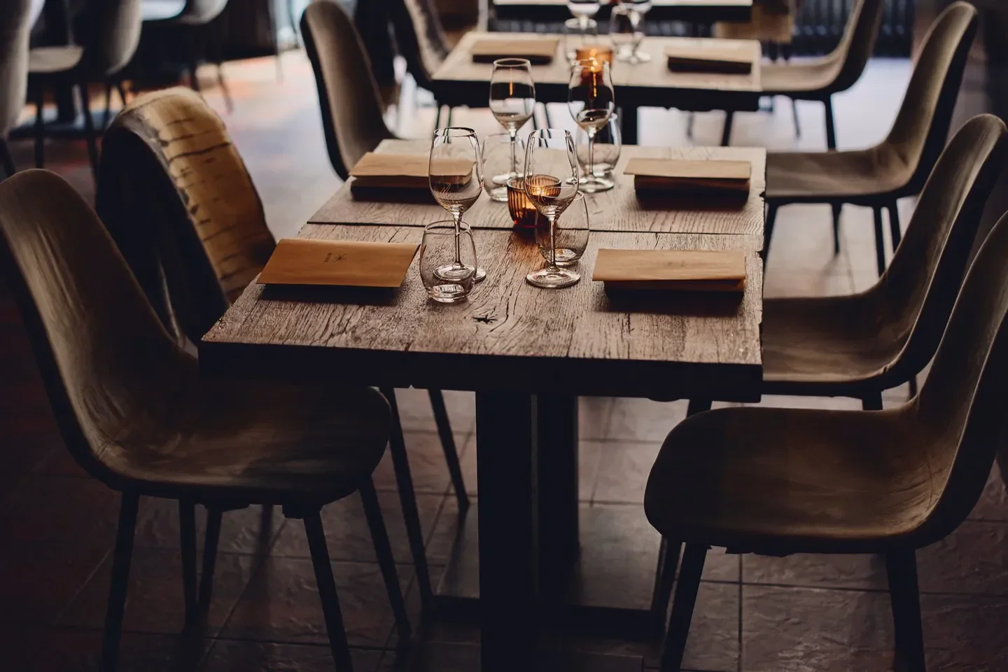 Cozy dining area at Natura in Helsinki, featuring wooden tables, chairs, and candlelight.