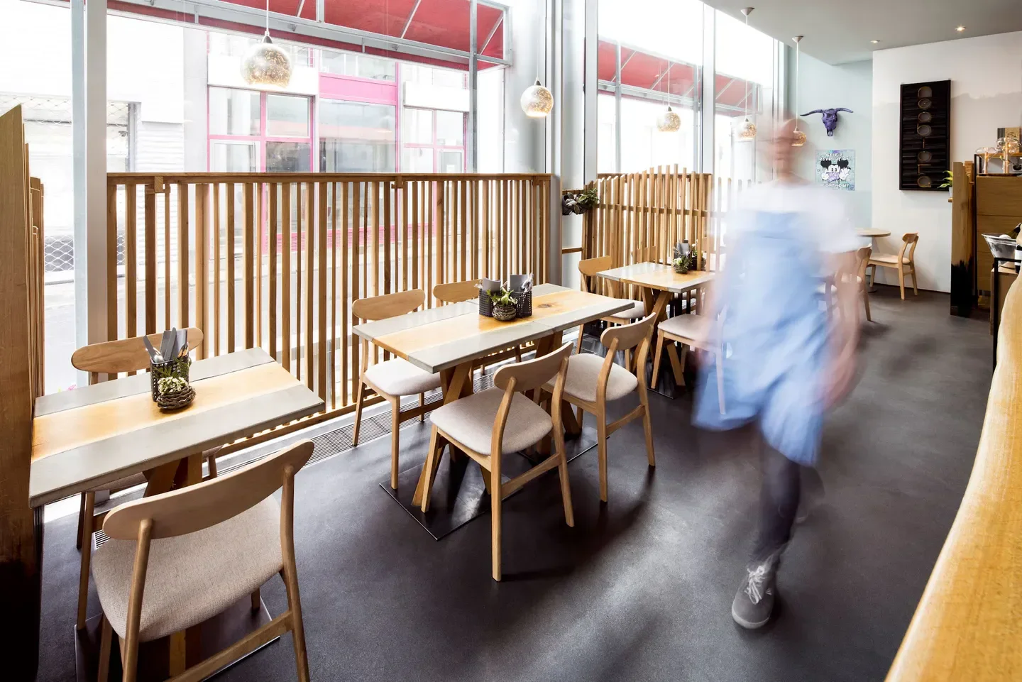 Modern interior of NeoBiota restaurant in Cologne with wooden tables and blurred motion.