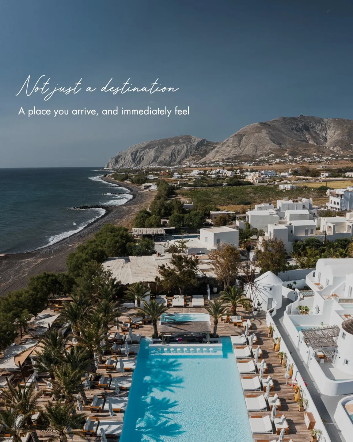 Aerial view of Nikki Beach Santorini's luxurious poolside and beachside resort with a stunning ocean backdrop