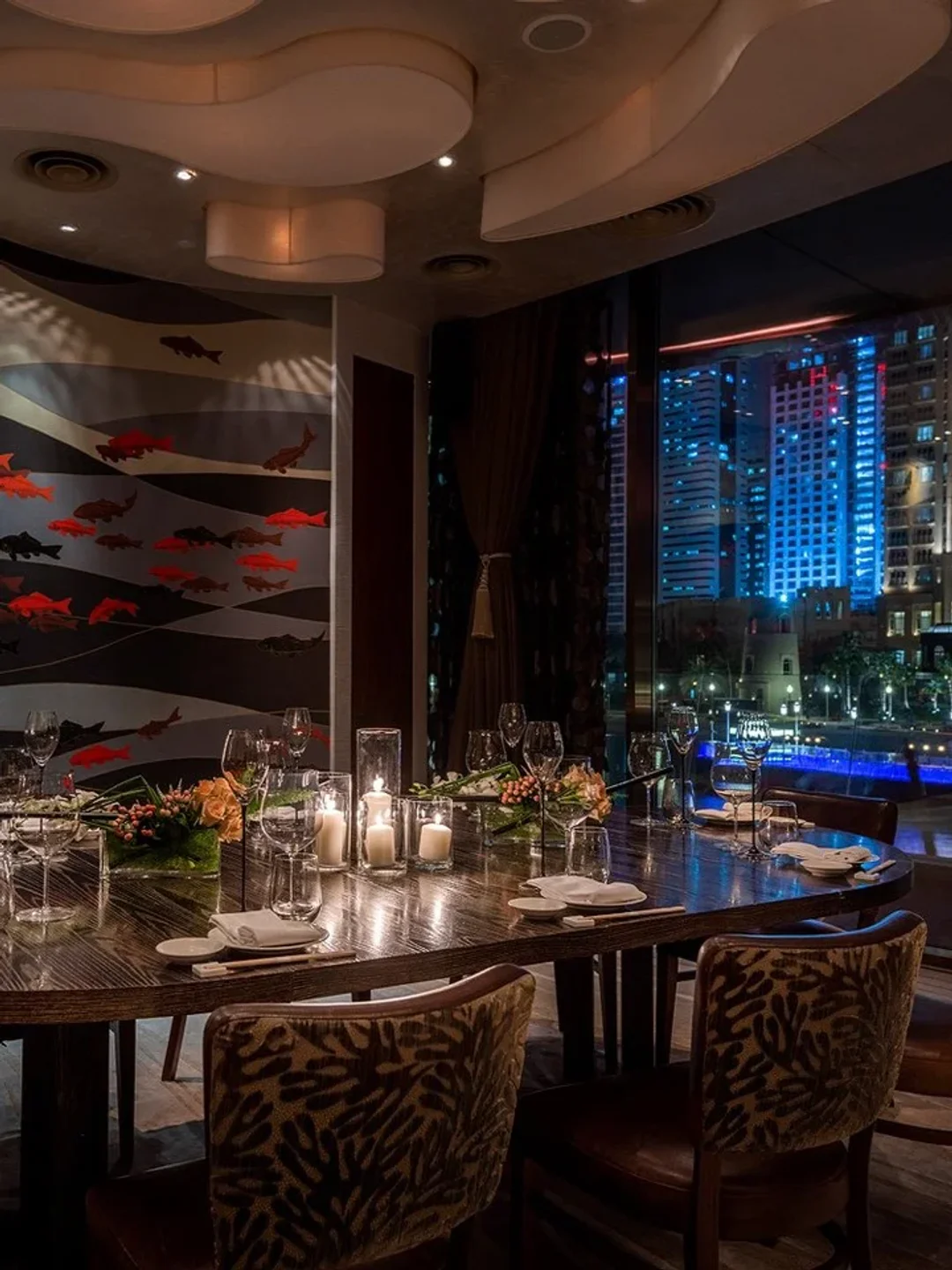 Elegant dining table at Nobu Doha with cityscape view and artistic fish mural