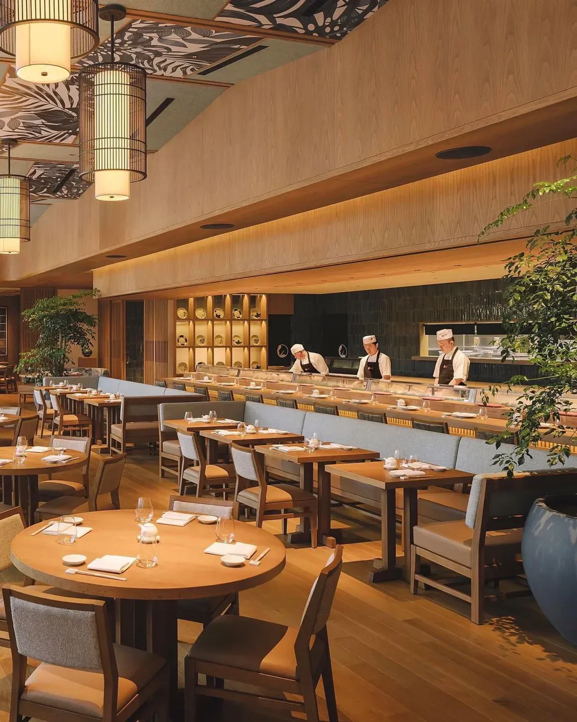 Interior of Nobu Singapore restaurant, featuring sushi chefs and dining tables.