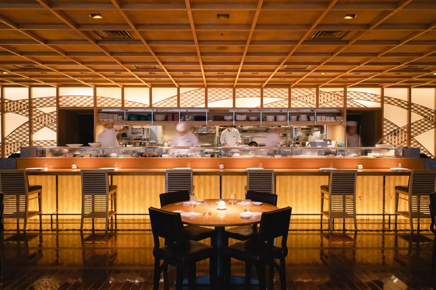 Interior view of Nobu Tokyo with sushi chefs at work and elegant dining tables.