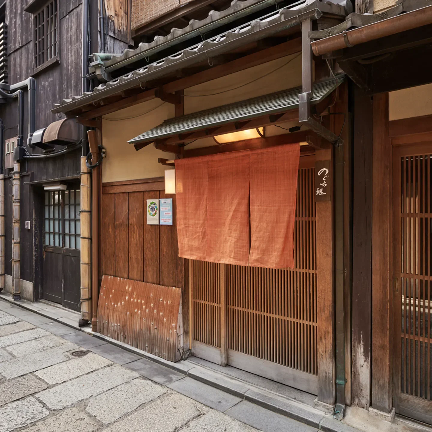 Entrance of Noguchi Tsunagu restaurant in Kyoto with traditional wooden facade and orange curtain