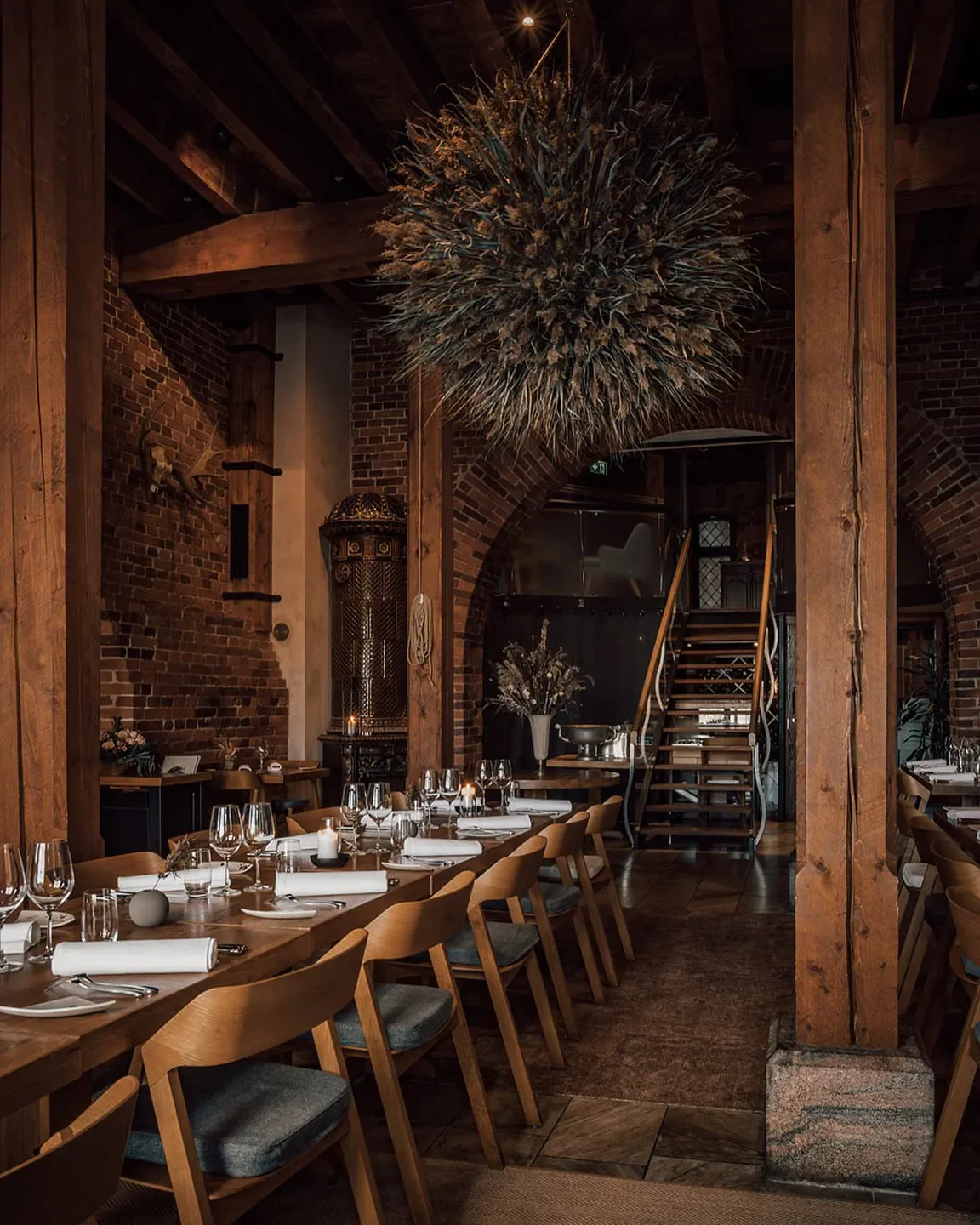 Cozy dining area at Nokka restaurant in Helsinki, featuring wooden beams and brick walls.