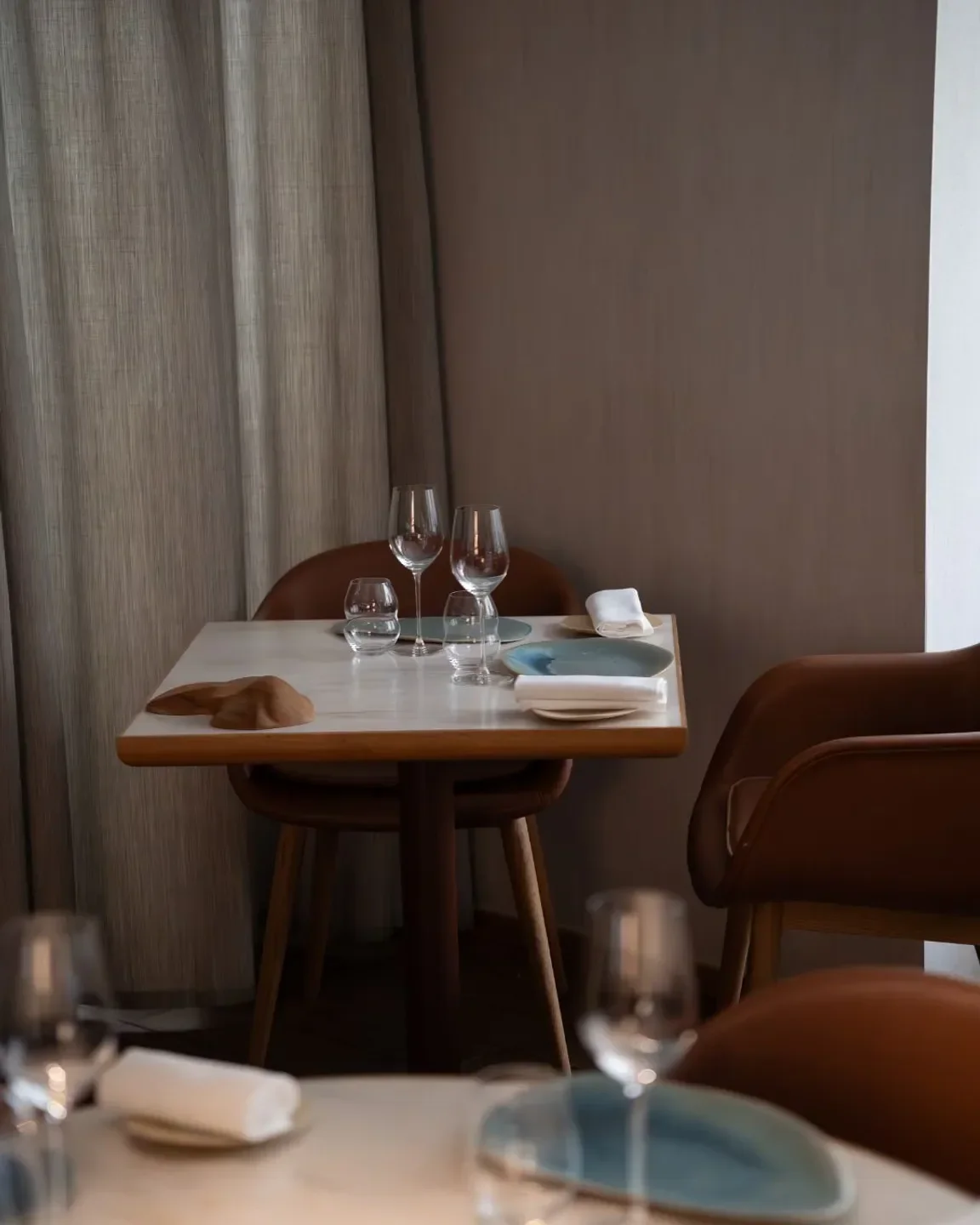 Elegant table setting at Nomicos restaurant in Paris, featuring glasses and a stylish interior.