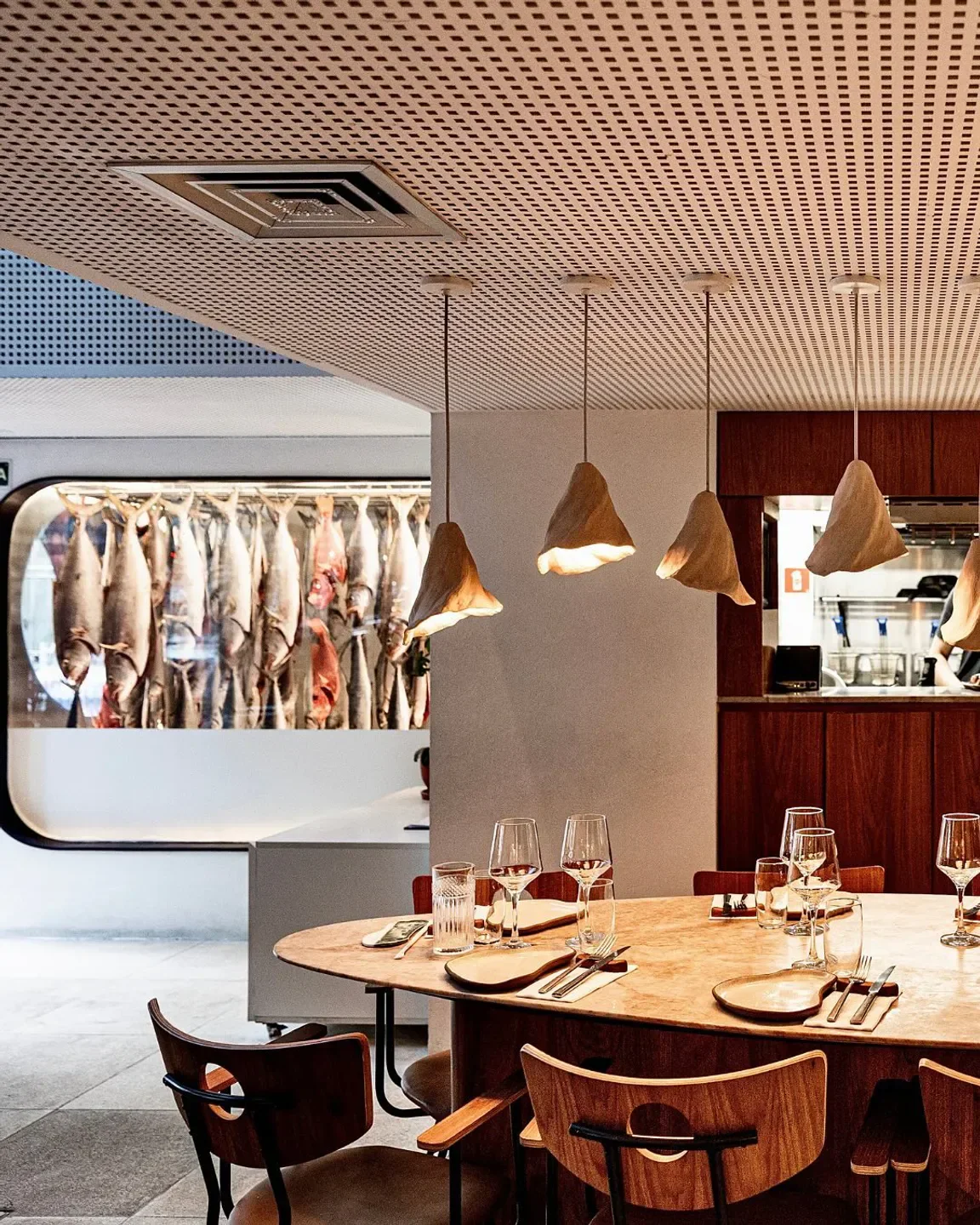 Elegant dining at Ocyá restaurant in Rio de Janeiro, with hanging fish and stylish decor.