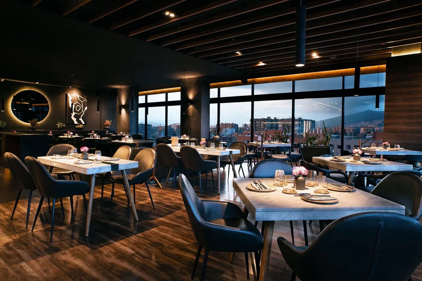 Interior of Oda restaurant in Bogota with tables set, city views, and modern design.
