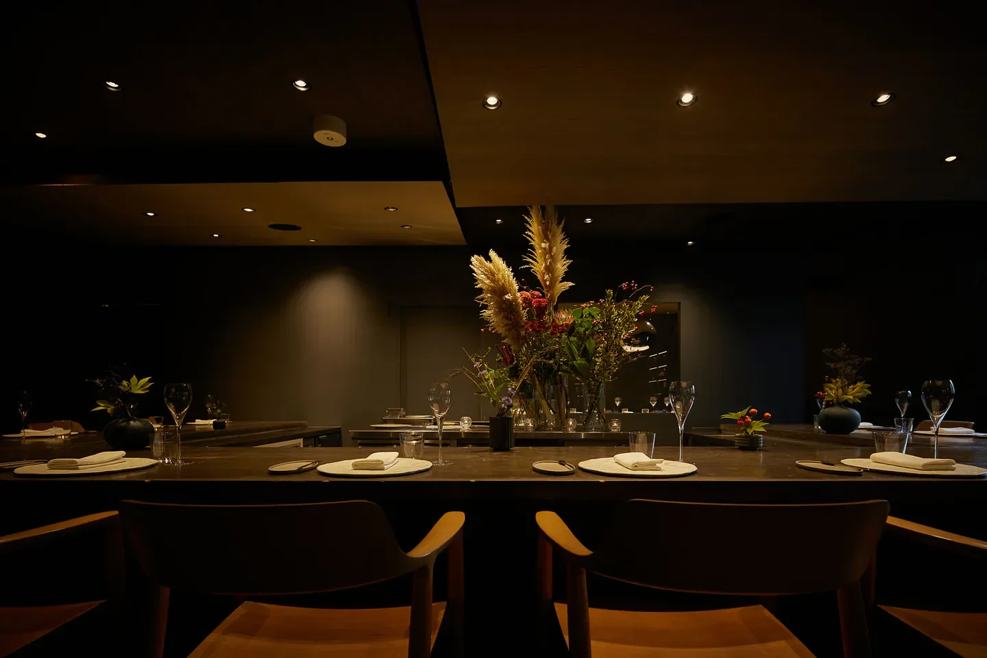 Elegant dining room interior at Ode, a Tokyo restaurant, with floral centerpiece and place settings.