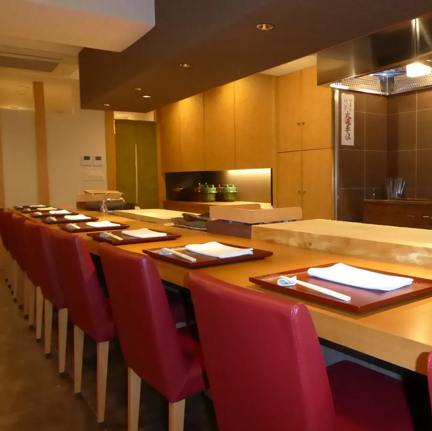 Interior of Okamoto restaurant in Tokyo, showcasing elegant sushi bar and seating with red chairs.