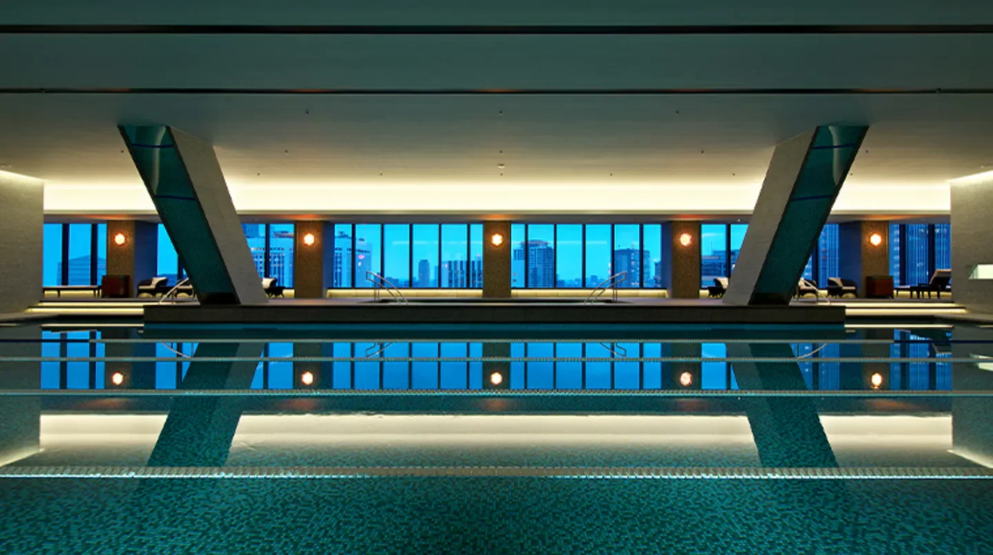 Indoor pool at Okura Fitness & Spa in Tokyo with city views through large windows