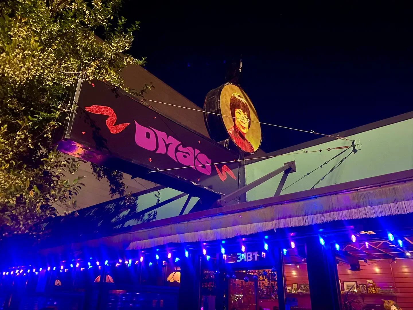 Oma's Hideaway restaurant in Portland, illuminated sign at night with string lights.