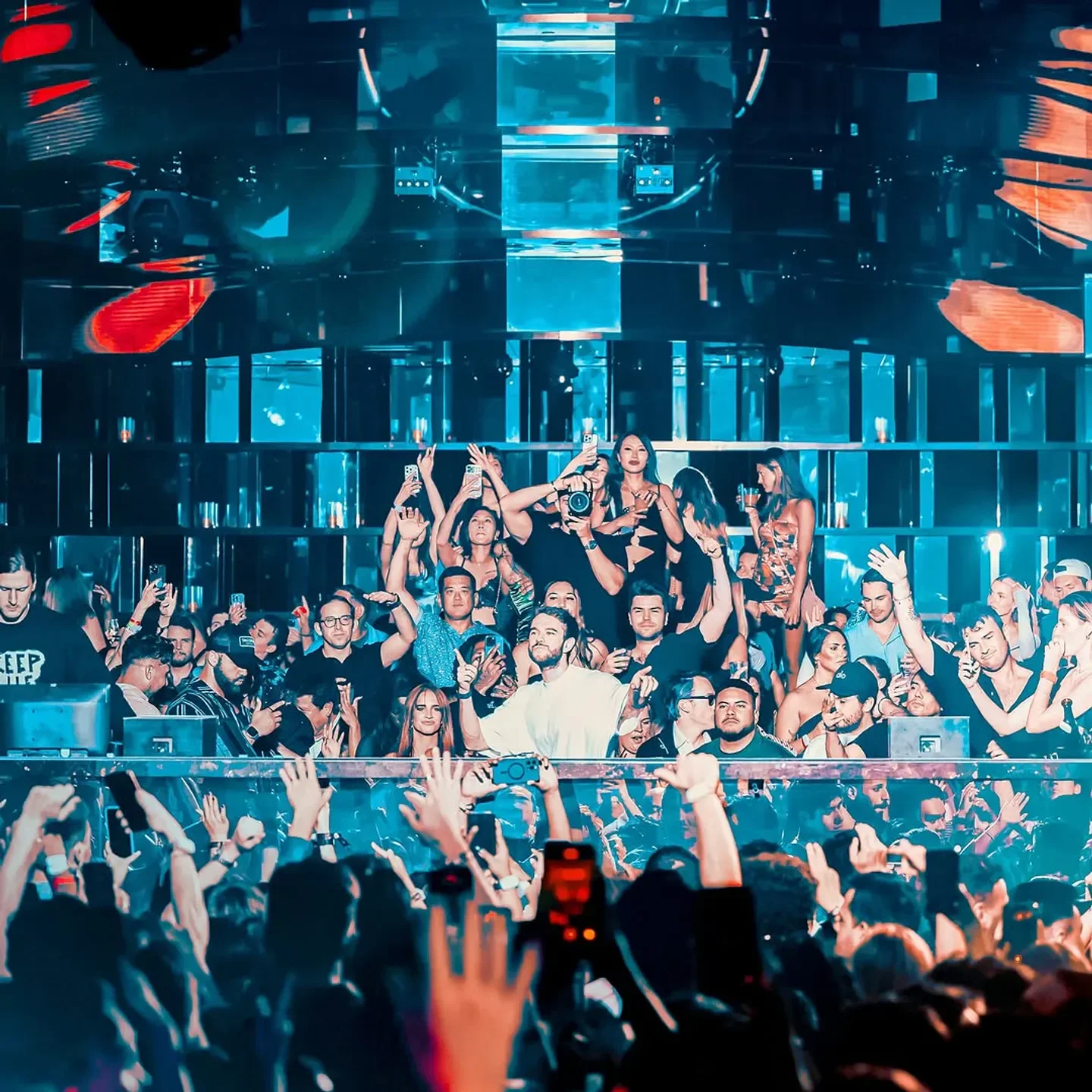 Energetic crowd at Omnia nightclub in Las Vegas with raised hands and vibrant lights.