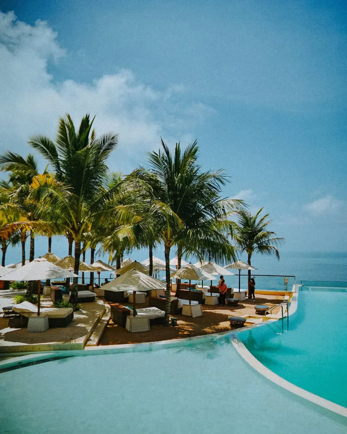 Luxury beach club with an infinity pool at Oneeighty in Bali, palm trees and ocean views