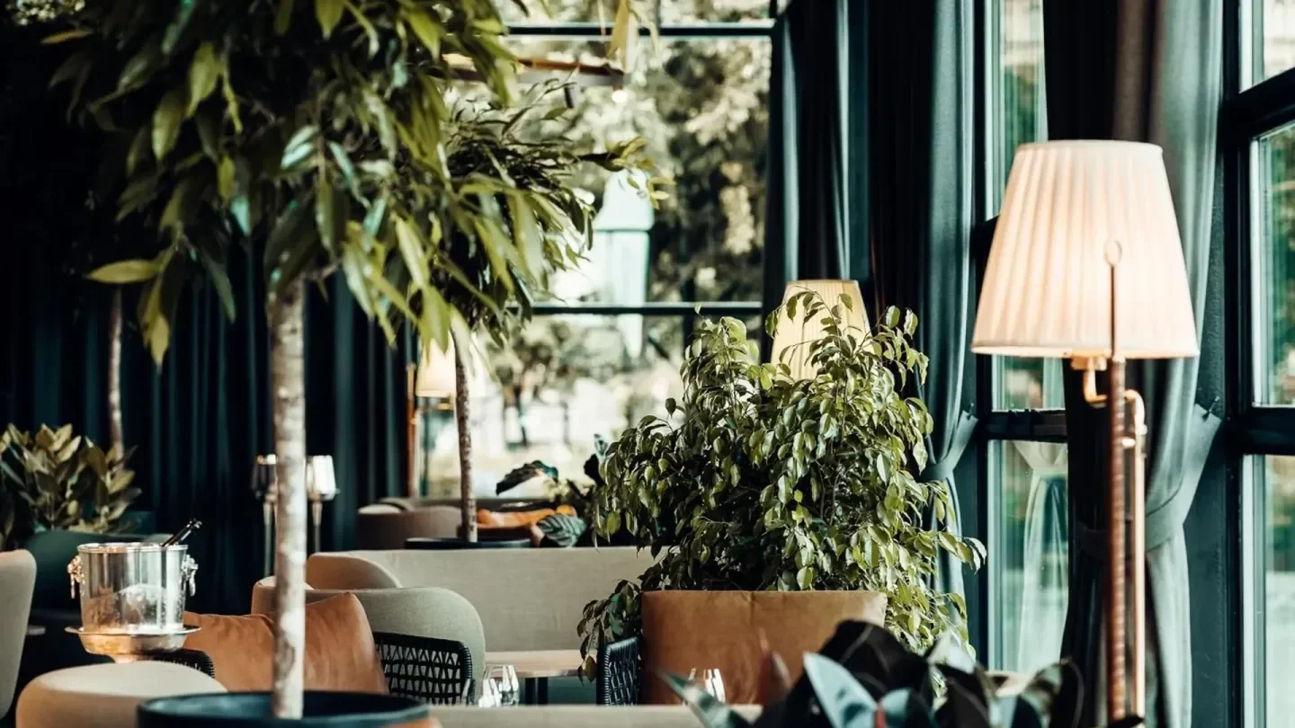 Elegant interior of Operakällaren restaurant in Stockholm with lush greenery and lamps.