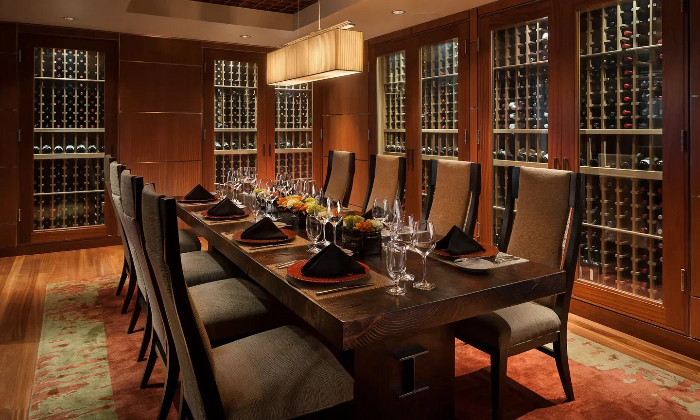 Elegant dining room at Orange Sky in Phoenix, showcasing wine cellar and exquisite table setting.