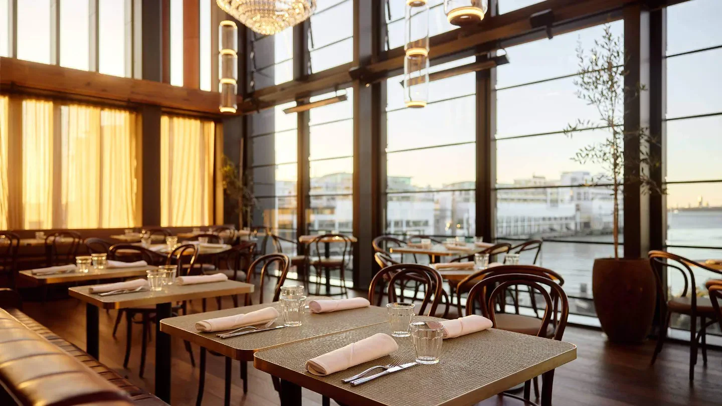 Interior of Origine restaurant in Auckland, with tables set by a large window.