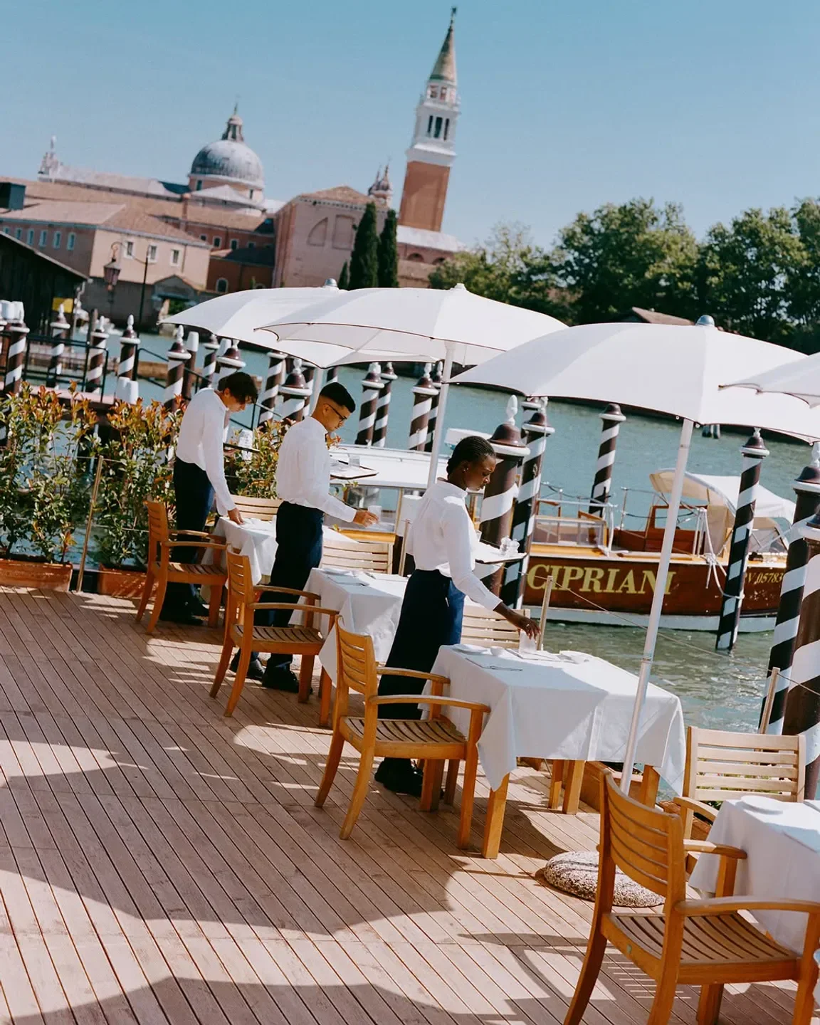 Oro Restaurant in Venice, waiters setting tables on a waterside terrace.