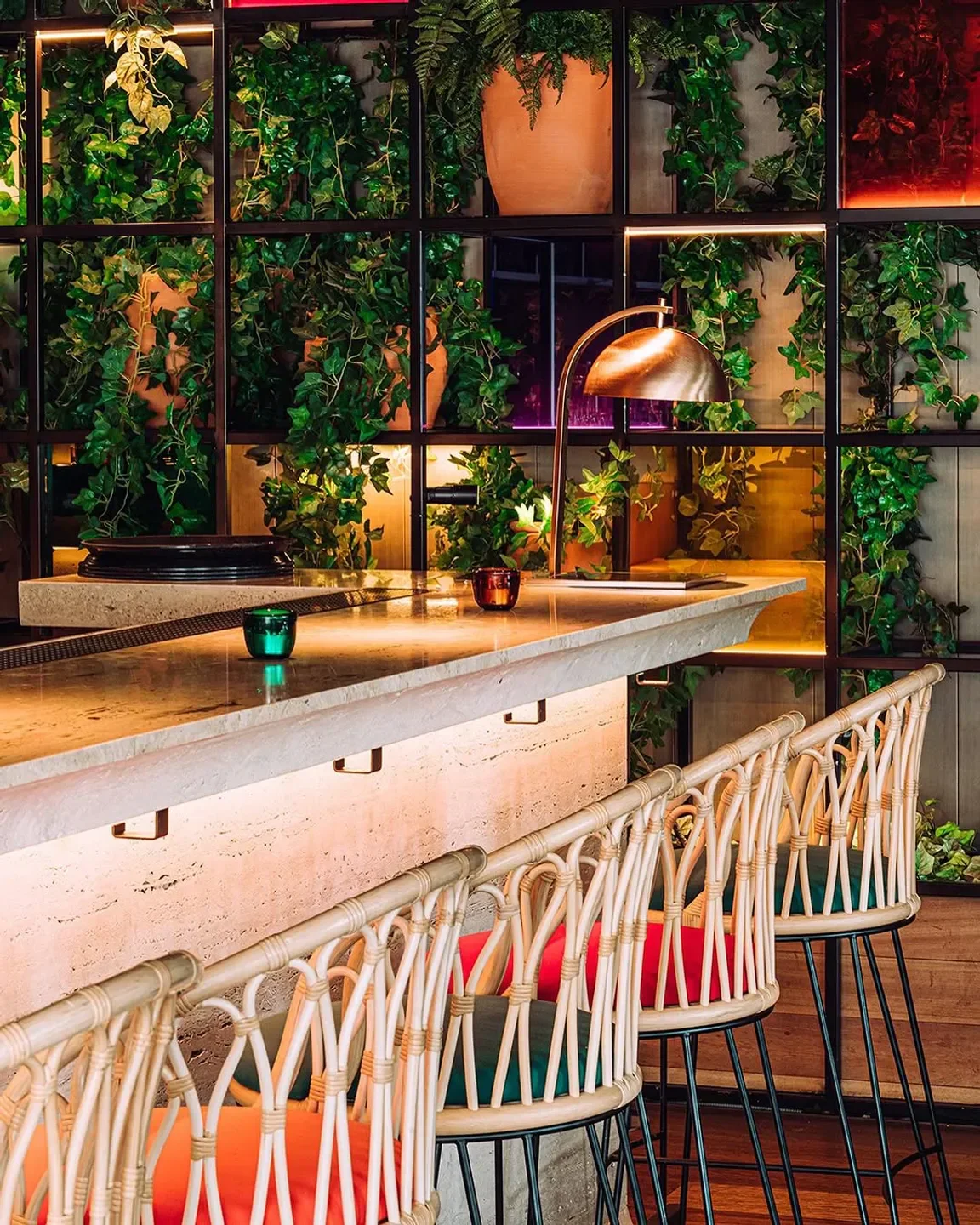 Stylish bar at Oroya Madrid with rattan chairs and greenery, perfect for dining.
