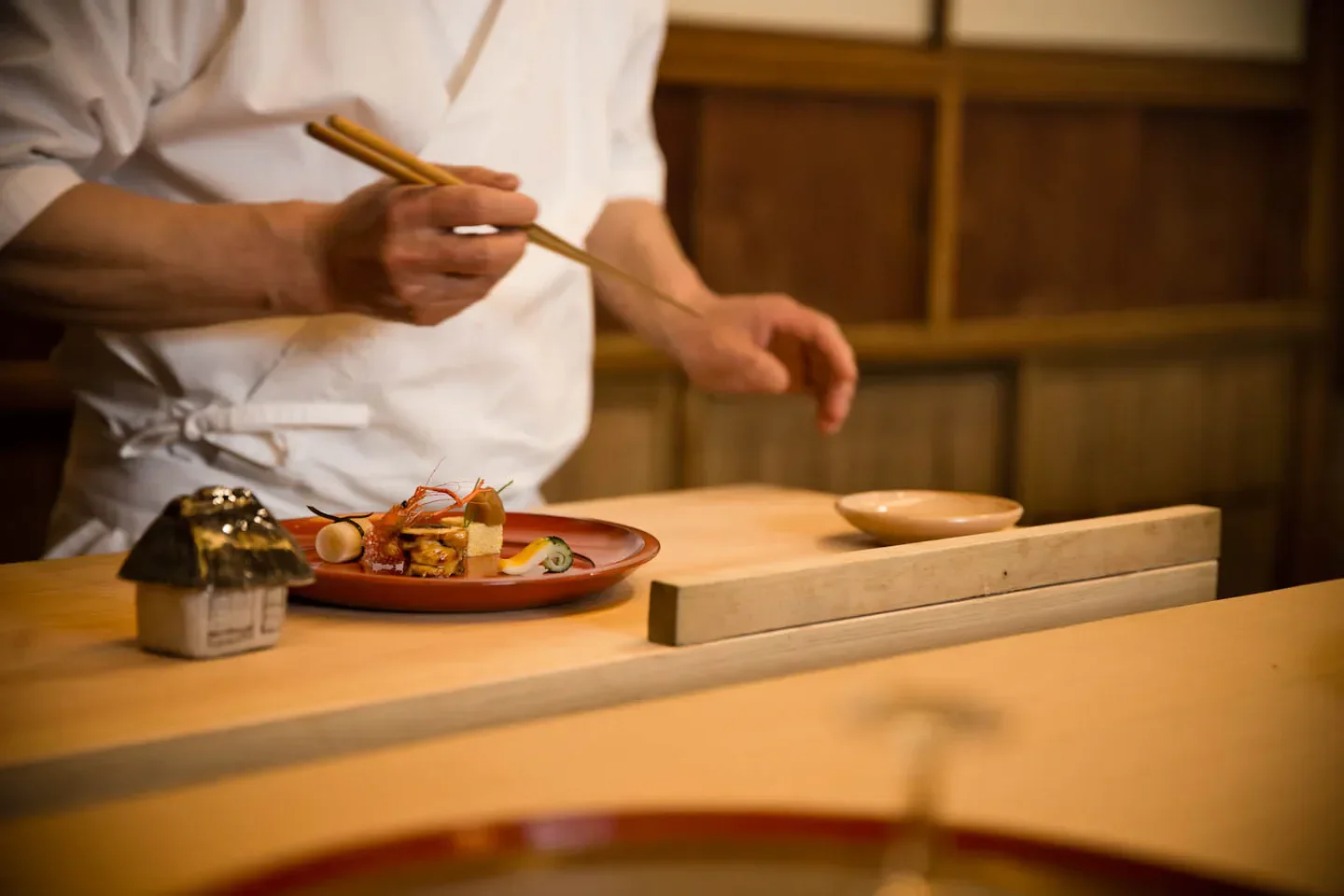 Chef preparing a dish at Oryori Hayashi restaurant in Kyoto, with chopsticks and food.