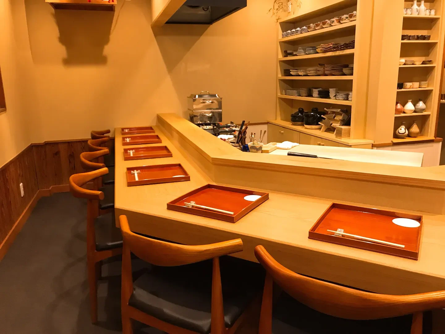 Cozy counter seating at Oryori Hirooka restaurant in Nara, with wooden chairs and serving trays.