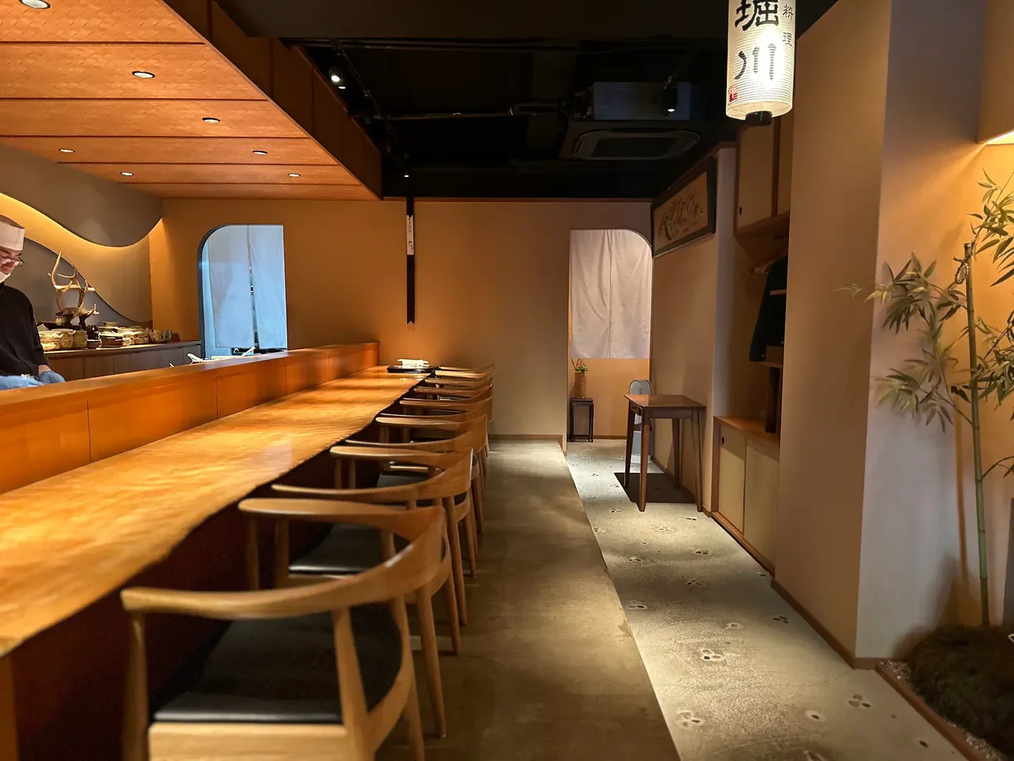Interior of Oryori Horikawa restaurant in Osaka, showcasing wooden seating and a sleek design.