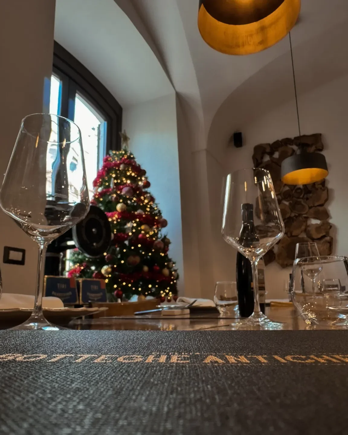 Cozy holiday dining at Osteria Botteghe Antiche in Puglia, featuring wine glasses and festive decor.