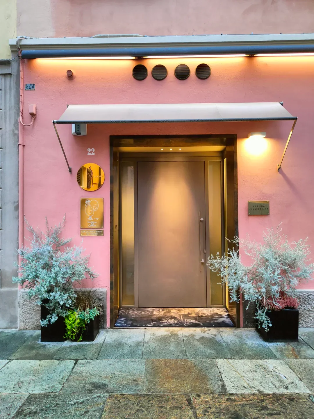 Entrance of Osteria Francescana in Modena, with pink facade and elegant door.