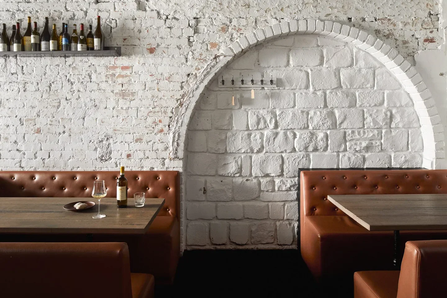 Interior of Osteria Ilaria in Melbourne featuring white brick walls and leather booths.