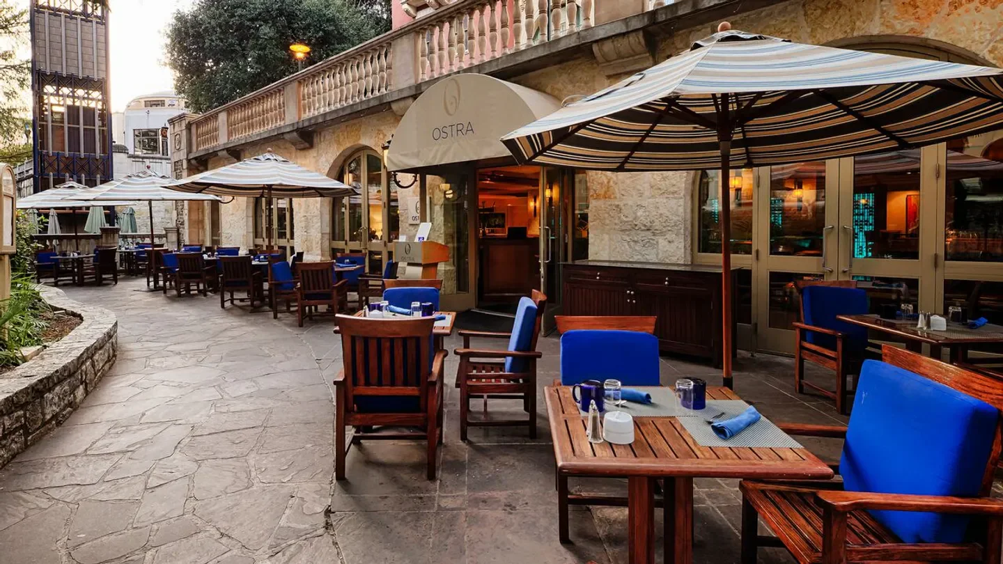 Outdoor seating at Ostra San Antonio restaurant with blue cushions and striped umbrellas