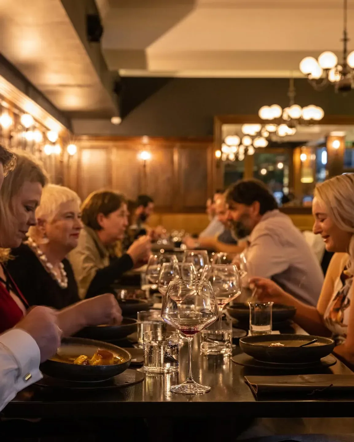 Dining scene at OTIS Dining Hall in Canberra, featuring meals, wine glasses, and guests.