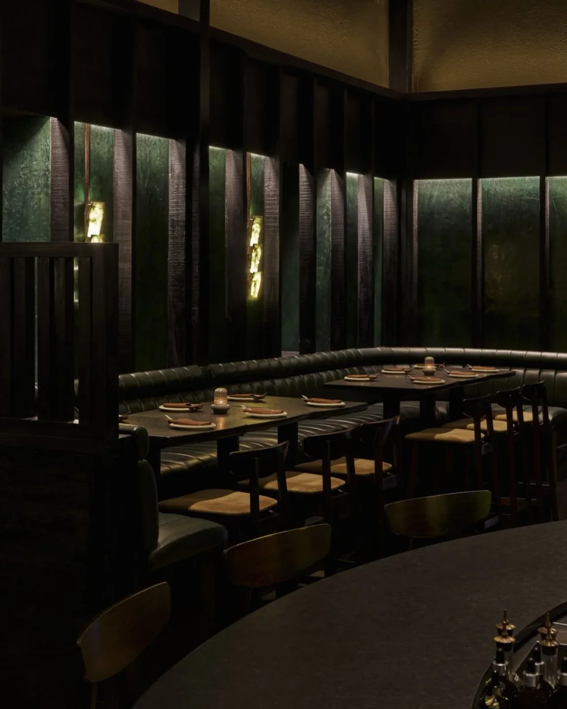Dimly lit interior of Otra restaurant in the city, featuring plush booth seating and modern decor.
