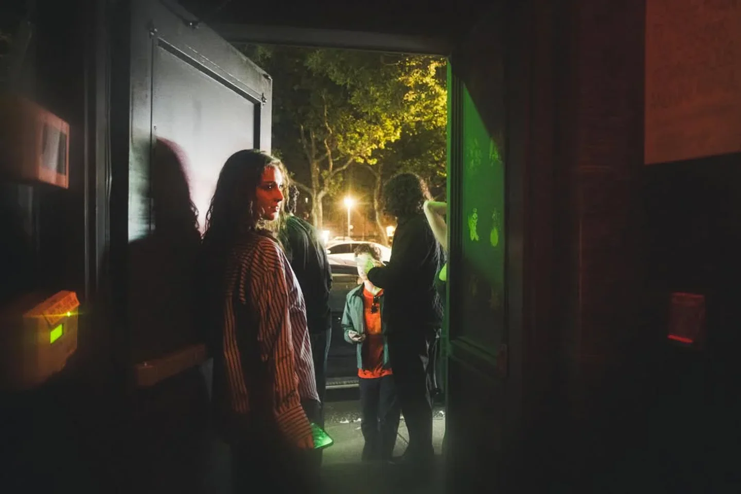 People entering Outer Heaven nightclub at night, with green and red lighting creating a moody atmosphere.