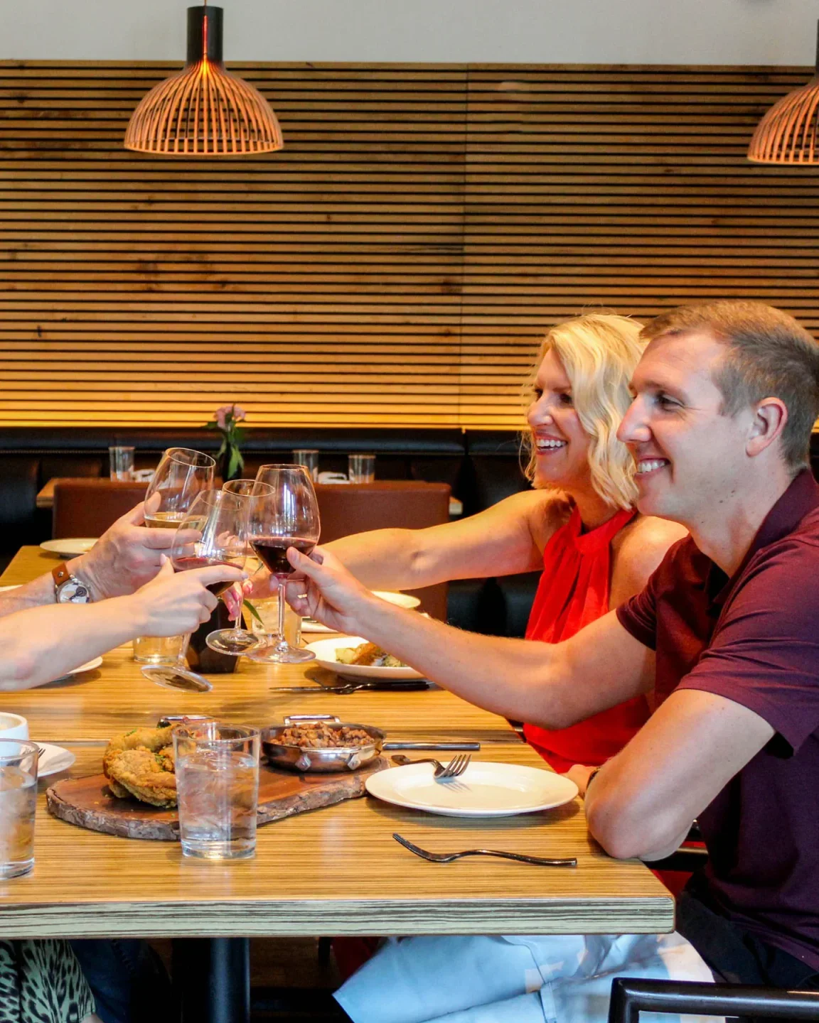 Cheers at Ovide in Florida Panhandle restaurant. Diners raise wine glasses for a toast.