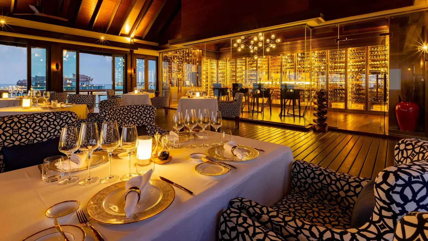Elegant restaurant interior at Ozen Reserve Bolifushi, Maldives, with wine cellar and sea view.