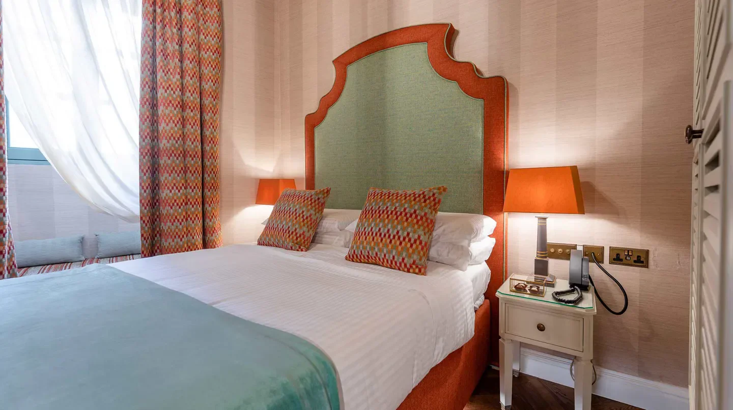 Cozy bedroom at Palazzo Bifora hotel in Malta, featuring a stylish headboard and lamps.