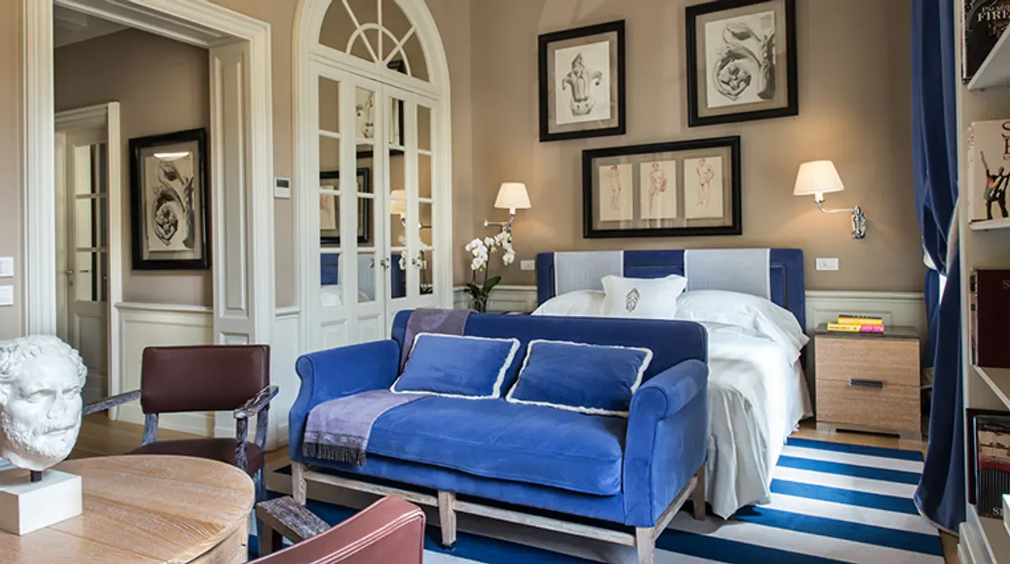 Cozy bedroom interior at Palazzo Vecchietti in Florence, featuring blue accents and art.