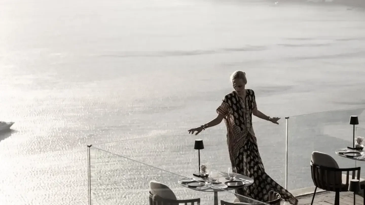 Woman on Panorama Terrace, Santorini, overlooking the sea at this elegant restaurant.