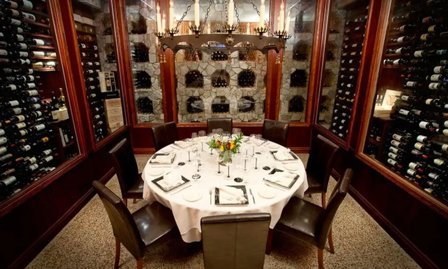 Cozy dining room at Paradiso Ristorante in Palm Beach with wine cellar and set table.
