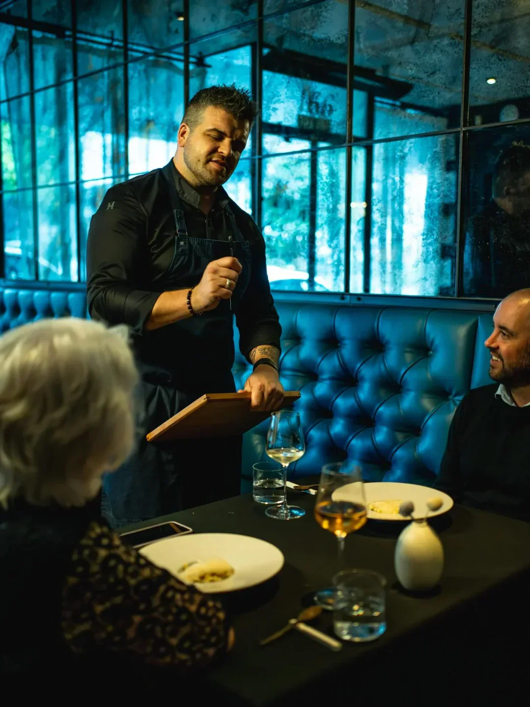 Chef presenting dish to diners at Paris Butter restaurant in Auckland, New Zealand.