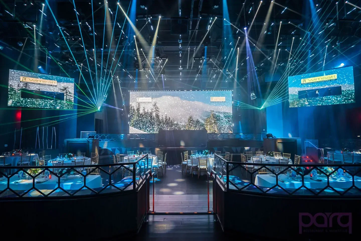 Inside Parq nightclub in San Diego with stage, lights and tables set for dining.