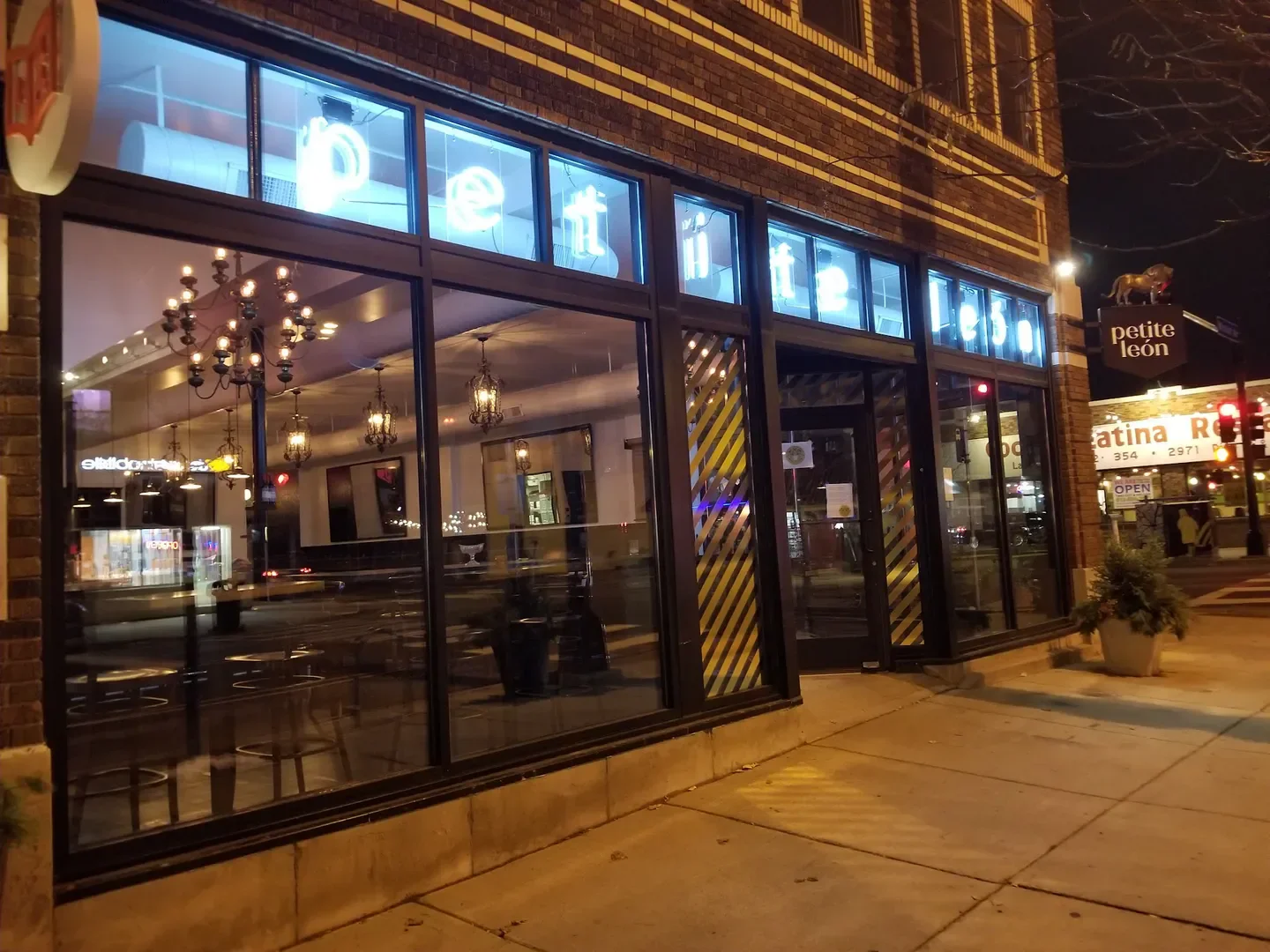 Exterior view of Petite León restaurant in Minneapolis at night with illuminated signage.