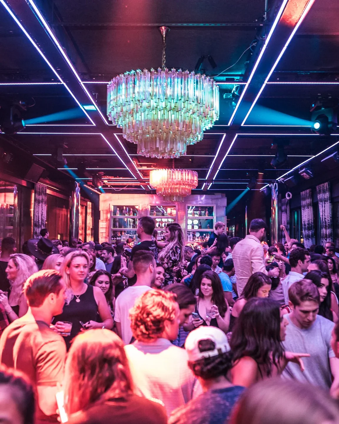 Lively crowd enjoying the nightlife at PHD Rooftop in New York City under a glamorous chandelier.